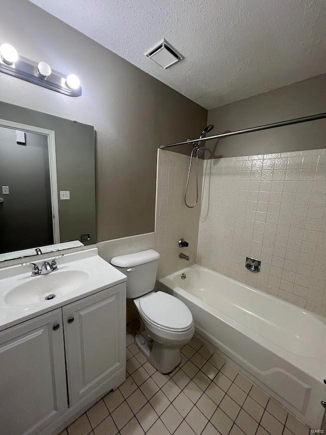 full bathroom with tiled shower / bath, vanity, toilet, tile patterned floors, and a textured ceiling