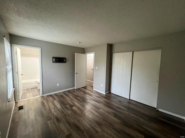 unfurnished bedroom with dark wood-type flooring, a textured ceiling, and a closet