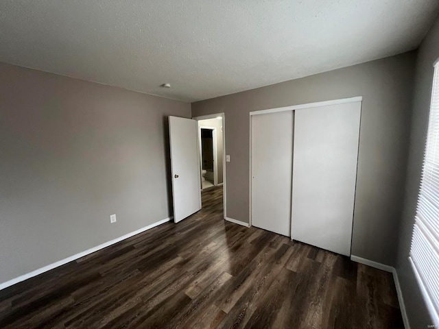 unfurnished bedroom with dark wood-type flooring, a closet, and a textured ceiling