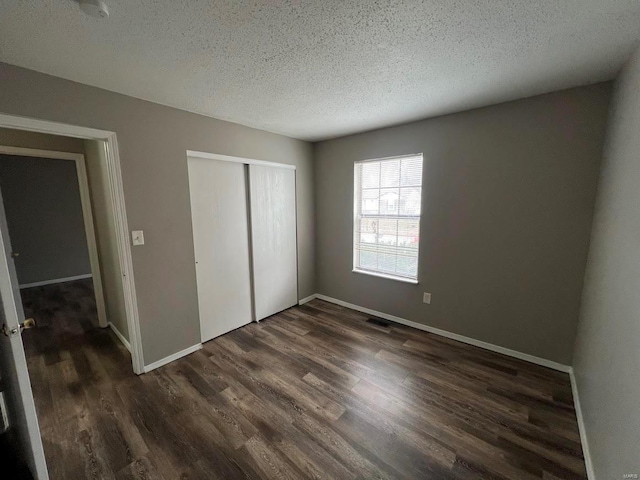 unfurnished bedroom with dark hardwood / wood-style floors, a closet, and a textured ceiling