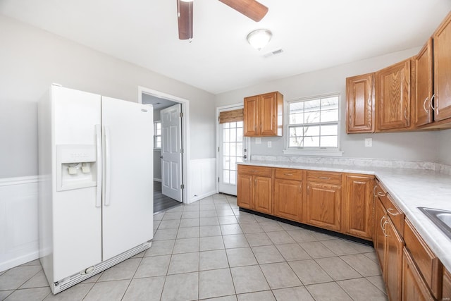 kitchen with white refrigerator with ice dispenser, light tile patterned floors, and ceiling fan