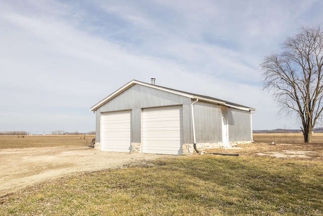 garage featuring a lawn and a rural view