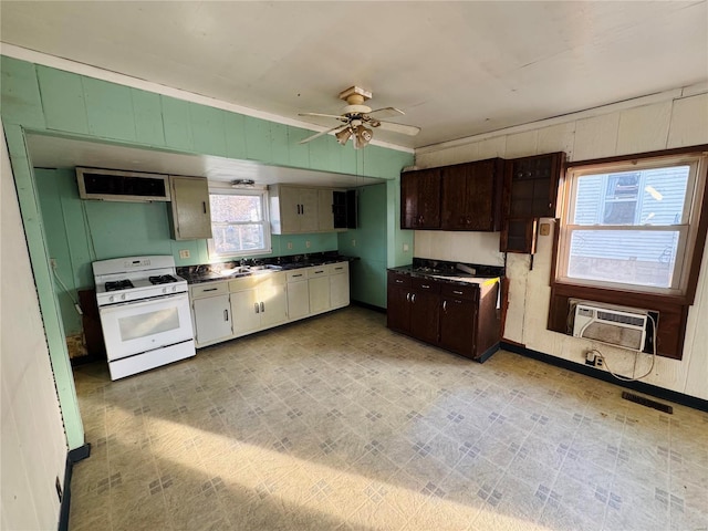 kitchen with sink, ceiling fan, white range with gas stovetop, dark brown cabinets, and an AC wall unit