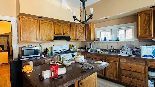 kitchen featuring sink, backsplash, white range with gas stovetop, a notable chandelier, and light wood-type flooring