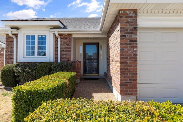 property entrance with a garage, brick siding, and a shingled roof