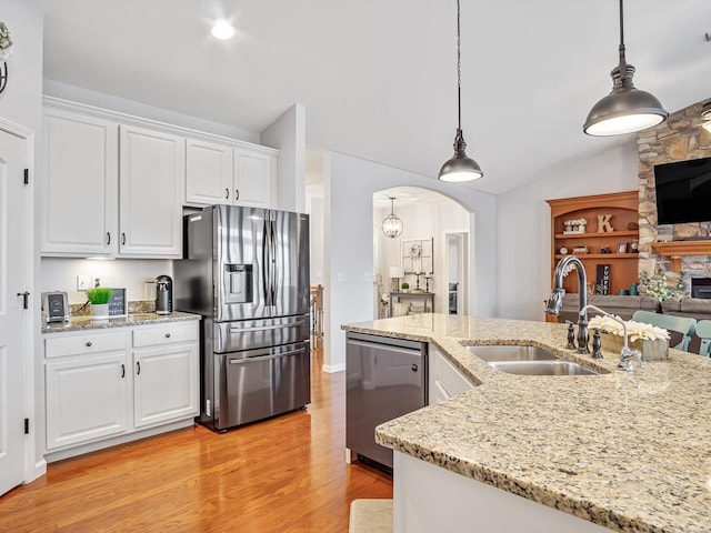 kitchen with appliances with stainless steel finishes, sink, pendant lighting, and white cabinets