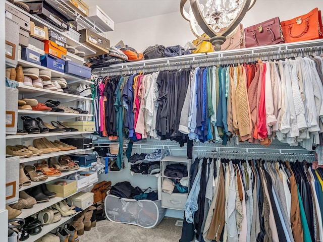 walk in closet featuring carpet flooring and a notable chandelier