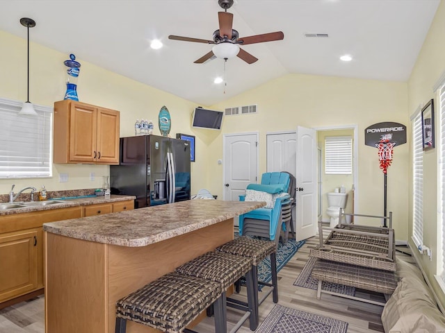 kitchen featuring lofted ceiling, black fridge with ice dispenser, sink, a kitchen island, and pendant lighting