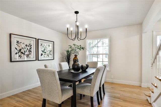 dining space with light hardwood / wood-style floors and a notable chandelier