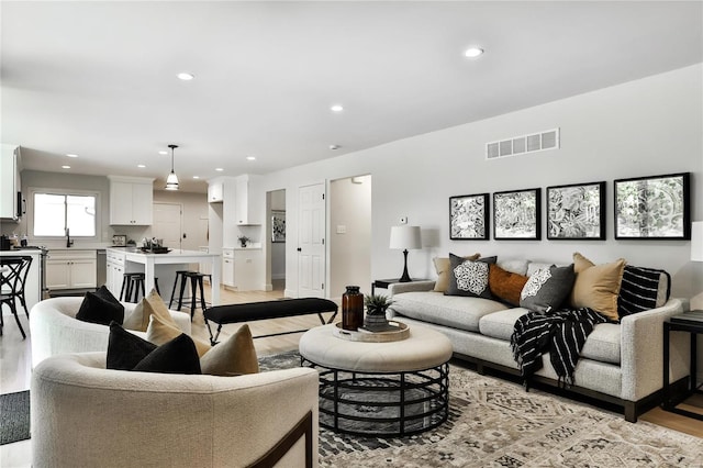 living room featuring sink and light hardwood / wood-style flooring