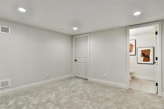 unfurnished bedroom with ensuite bath and light colored carpet