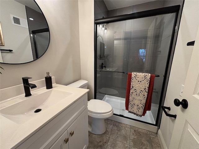 bathroom featuring vanity, a shower with door, and toilet