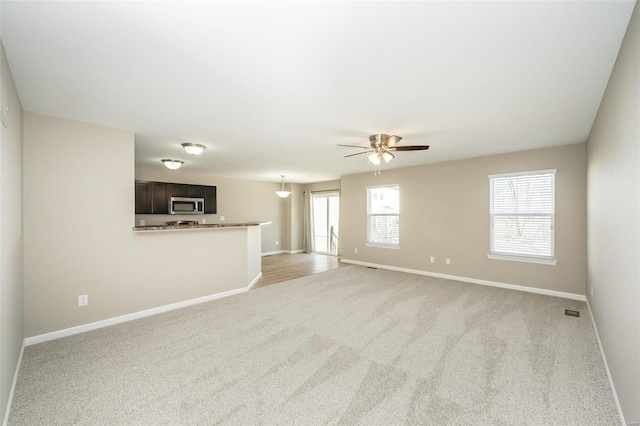 unfurnished living room with light carpet and ceiling fan