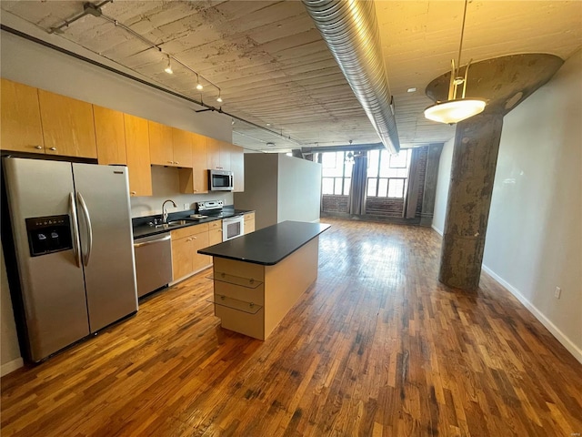 kitchen featuring rail lighting, sink, hanging light fixtures, appliances with stainless steel finishes, and hardwood / wood-style flooring