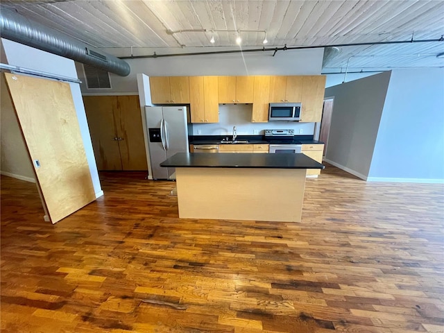 kitchen featuring sink, hardwood / wood-style floors, stainless steel appliances, a center island, and a high ceiling