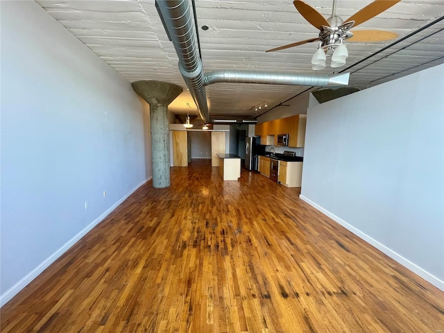 unfurnished living room featuring dark wood-type flooring and ceiling fan