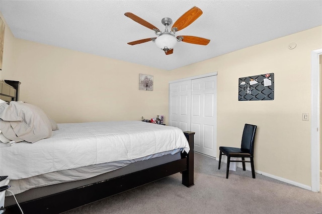 carpeted bedroom with ceiling fan, a closet, and a textured ceiling