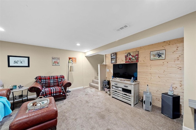 carpeted living room featuring wooden walls