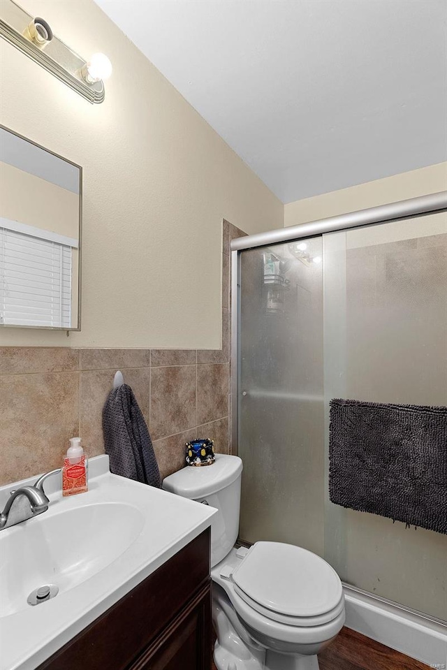 bathroom featuring vanity, toilet, an enclosed shower, and tile walls