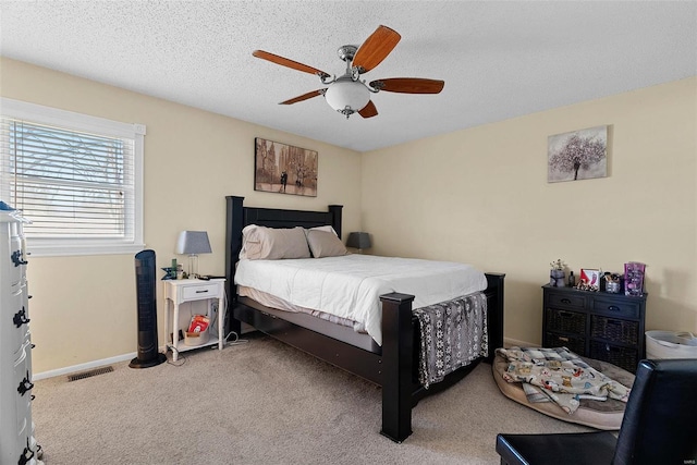 carpeted bedroom featuring ceiling fan and a textured ceiling