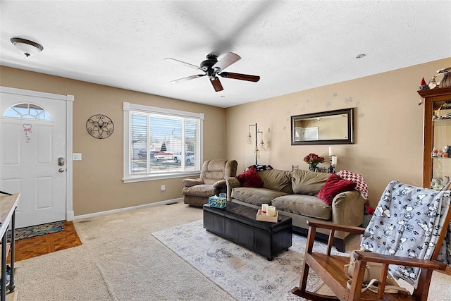 living room with light carpet, ceiling fan, and a textured ceiling