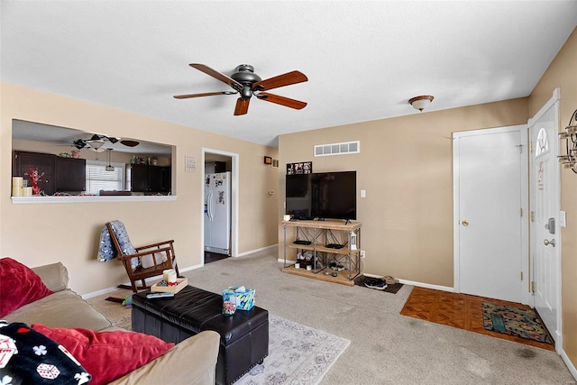 carpeted living room featuring ceiling fan and a textured ceiling