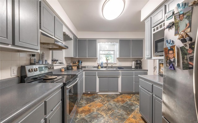 kitchen with gray cabinetry, backsplash, and appliances with stainless steel finishes