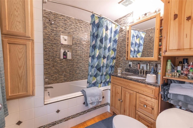 full bathroom with toilet, shower / tub combo, tile walls, vanity, and decorative backsplash