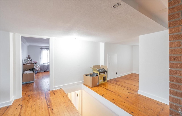 hall with hardwood / wood-style flooring and a textured ceiling