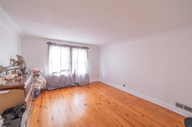 unfurnished bedroom featuring lofted ceiling and light hardwood / wood-style flooring