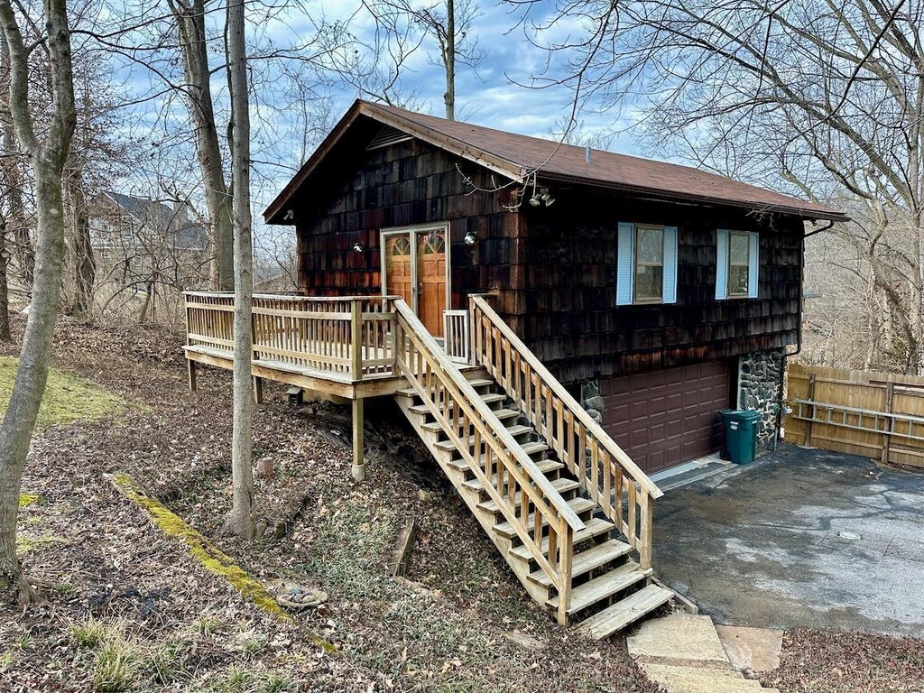 view of outdoor structure with stairway, a garage, driveway, and fence