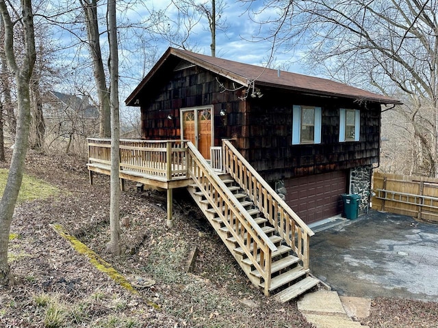 view of outdoor structure with stairway, a garage, driveway, and fence