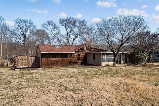 rear view of property featuring a yard and a sunroom