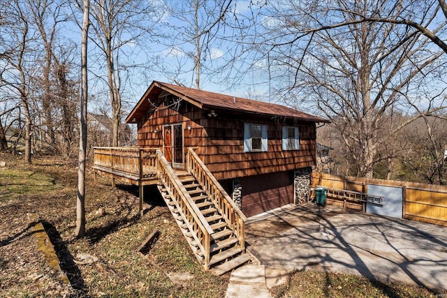 view of outbuilding featuring stairway, driveway, a garage, and fence