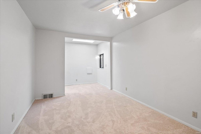 carpeted empty room with visible vents, baseboards, and ceiling fan