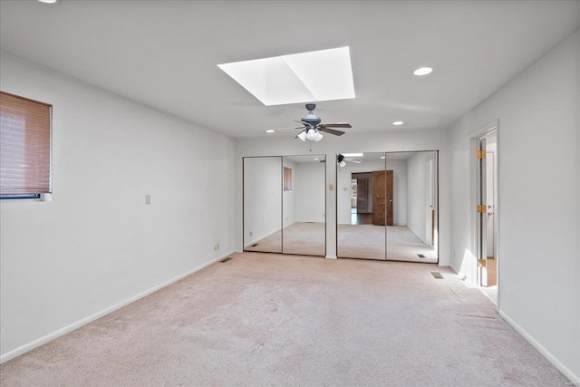 unfurnished bedroom featuring multiple closets, recessed lighting, carpet, a skylight, and baseboards