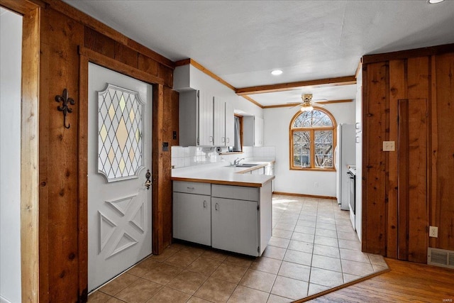 kitchen with visible vents, backsplash, light countertops, a ceiling fan, and a sink