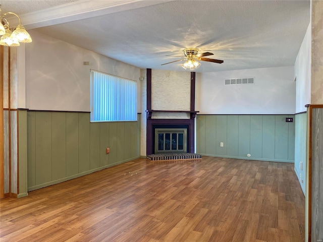 unfurnished living room with a fireplace, ceiling fan with notable chandelier, a textured ceiling, and light wood-type flooring