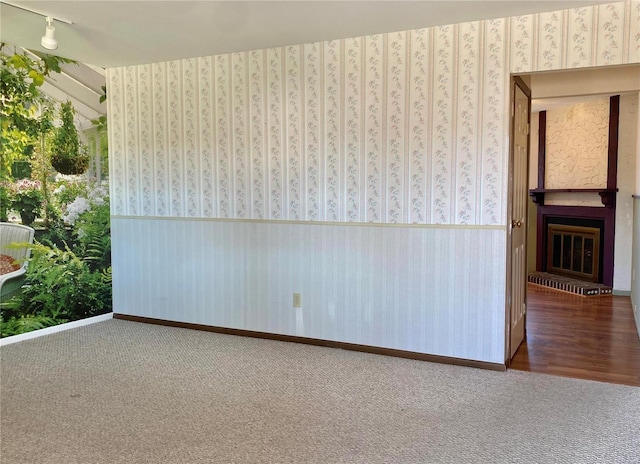 spare room featuring carpet flooring and a brick fireplace