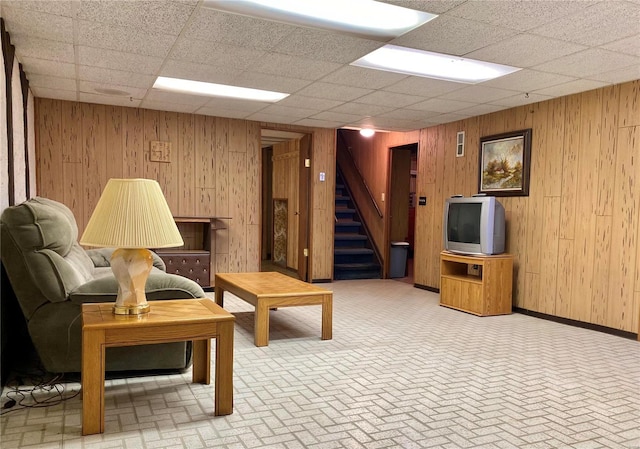 living room featuring wooden walls and a drop ceiling