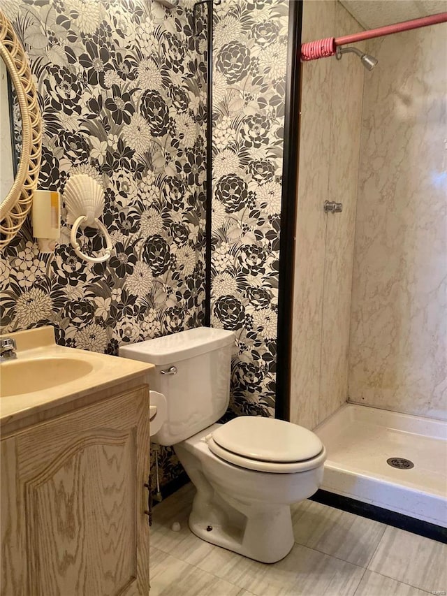 bathroom featuring vanity, toilet, and a tile shower