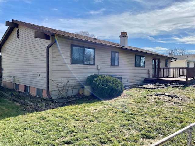 view of side of home with a wooden deck and a lawn