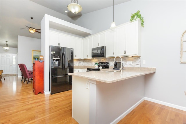 kitchen with decorative light fixtures, sink, white cabinets, and black appliances