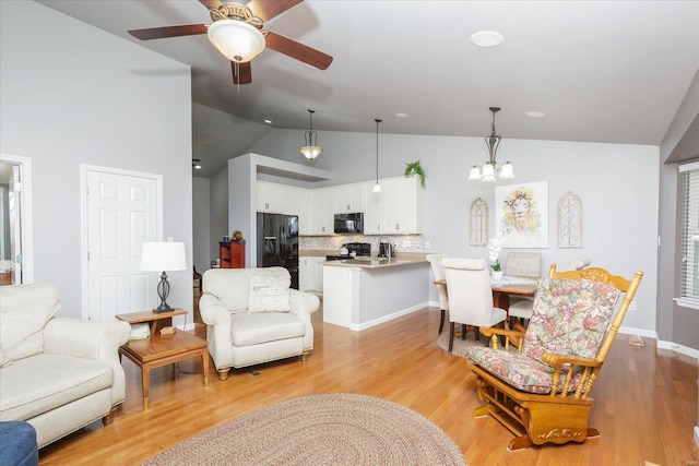 living room featuring high vaulted ceiling, ceiling fan with notable chandelier, and light wood-type flooring