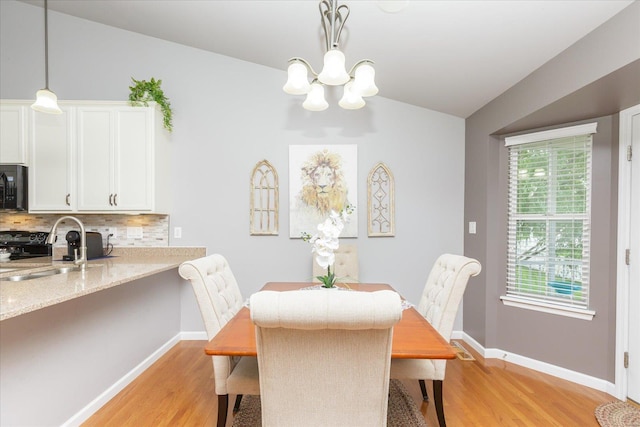 dining space featuring an inviting chandelier, lofted ceiling, sink, and light wood-type flooring