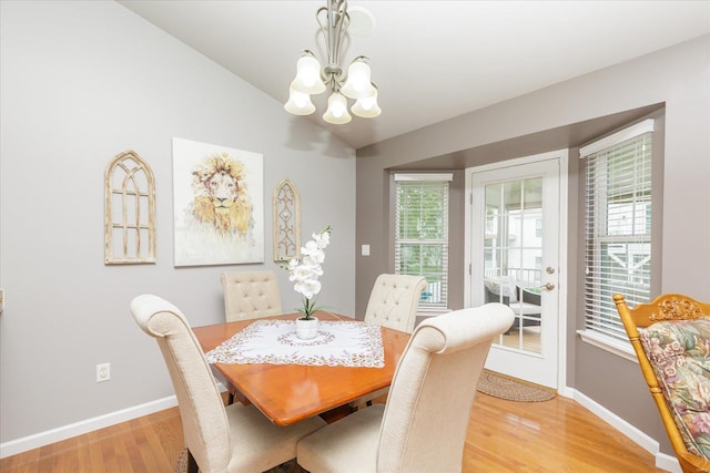 dining space with lofted ceiling, a chandelier, and light wood-type flooring