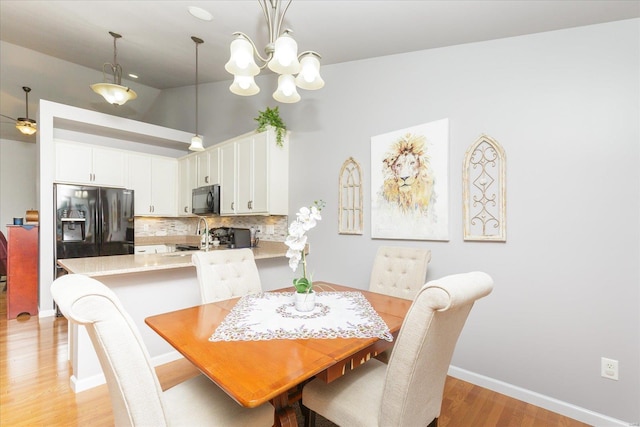 dining space featuring vaulted ceiling, a notable chandelier, and light wood-type flooring