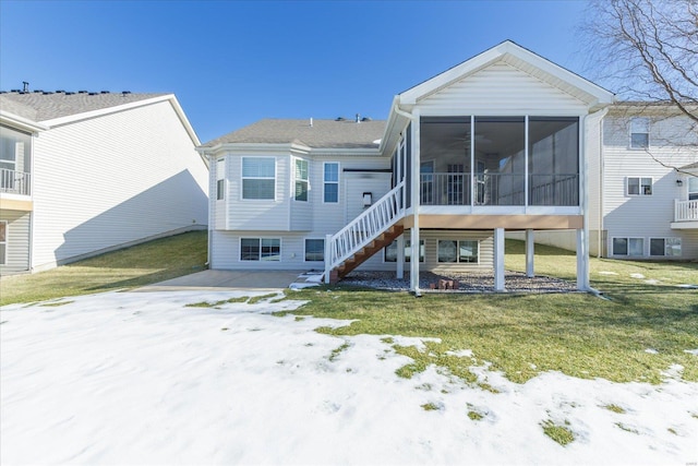 snow covered back of property with a yard and a sunroom