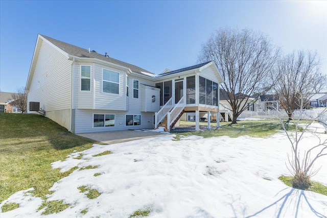 rear view of house with cooling unit, a patio area, a sunroom, and a lawn