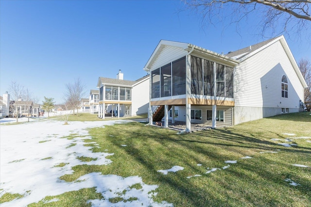 rear view of property with a yard and a sunroom